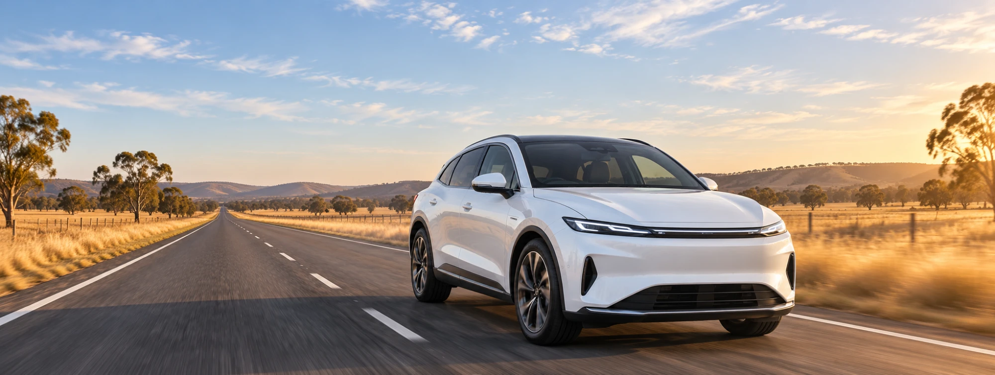 A white electric SUV on an open Australian country road at golden hour